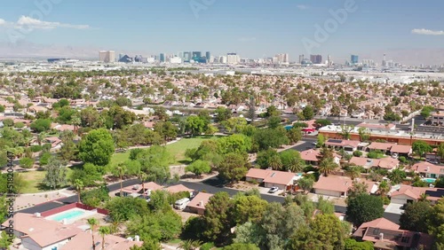Aerial pullback shot of Las Vegas homes with casino strip skyline and airport