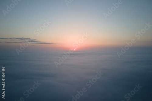 Aerial view from airplane window at high altitude of dense puffy cumulus clouds flying in evening