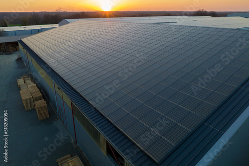 Aerial view of blue photovoltaic solar panels mounted on industrial building roof for producing green ecological electricity. Production of sustainable energy concept