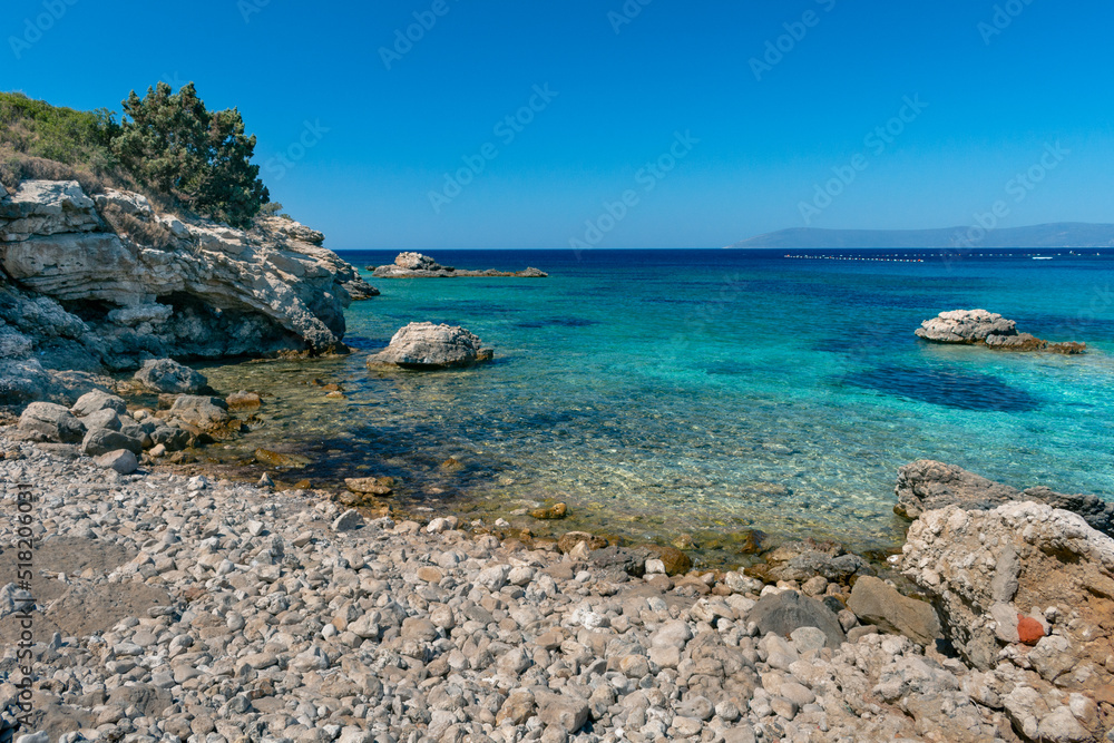 Amazing shot of a sea coast with clear blue water and stones in the foreground.