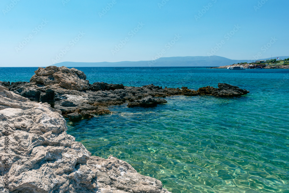 Amazing shot of a sea coast with clear blue water and stones in the foreground. Amazing shot of a sea coast with clear blue water and stones in the foreground.
