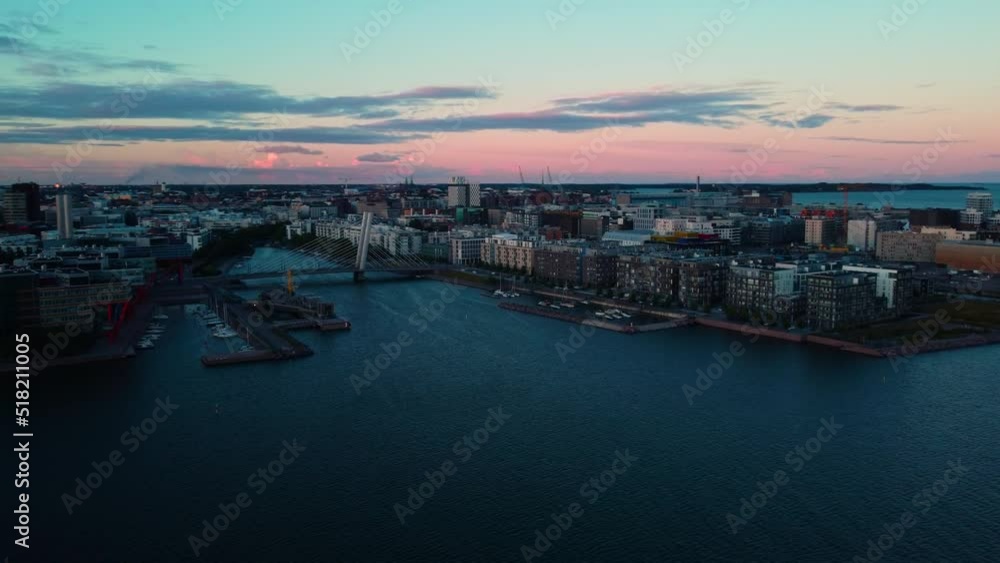 Aerial view around the Cruselli bridge, colorful dusk in Ruoholahti, Helsinki, Finland - circling, drone shot Aerial view around the Cruselli bridge, colorful dusk in Ruoholahti, Helsinki, Finland - circling, drone shot