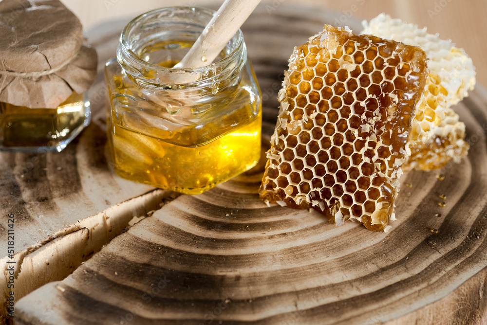jars of honey with honeycomb and dipper on wooden stump. jars of honey with honeycomb and dipper on wooden stump.
