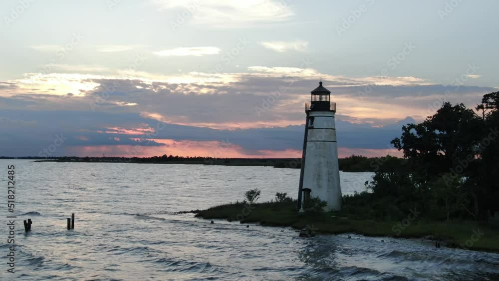 Drone shot back away from lighthouse at sunset near water on Lake Pontchartrain Drone shot back away from lighthouse at sunset near water on Lake Pontchartrain