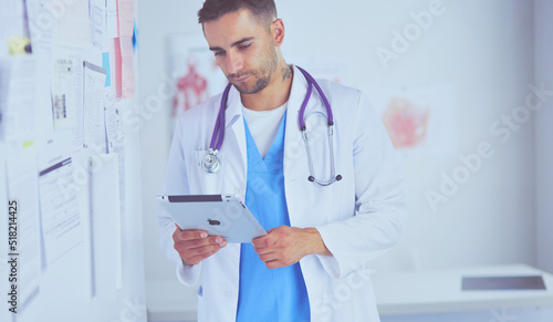 Young and confident male doctor portrait standing in medical office. photo