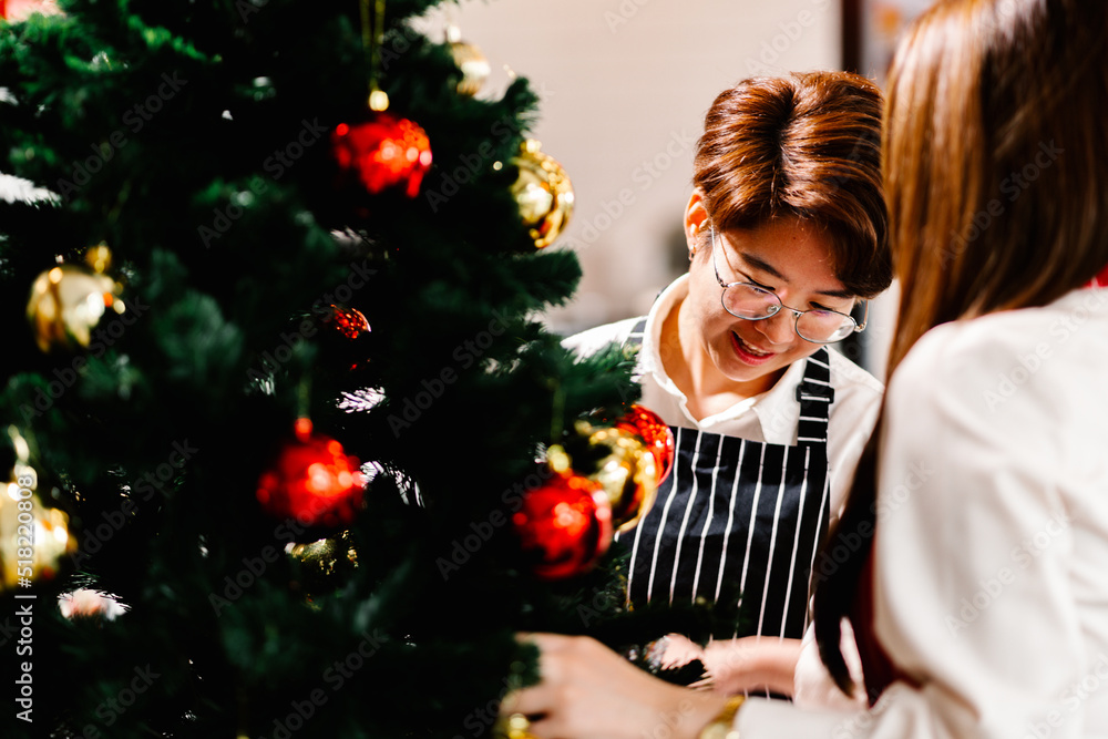 An apron-clad female employee and her buddies decorate the store's Christmas tree. Activity and Xmas celebrations