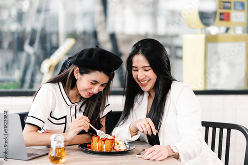 Asian woman enjoys eating a sweet dessert in a cafe with companion. Lifestyle and Cafe