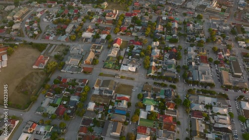Aerial descending footage of dense town development with family houses between streets. Scene lit by setting sun. Port Elisabeth, South Africa