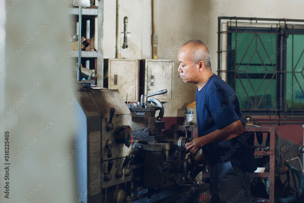 Technician asia worker using turning lathe machine for metalworking in workshop factory Technician asia worker using turning lathe machine for metalworking in workshop factory