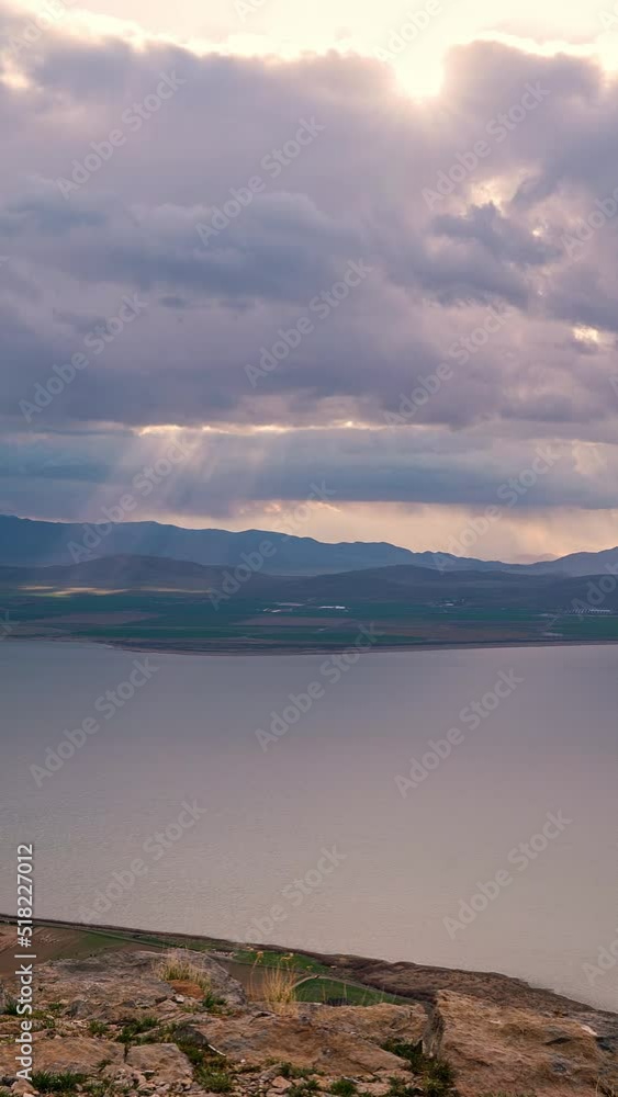 Storm clouds moving in the distance as light rays shine to the ground looking past Utah Lake. Storm clouds moving in the distance as light rays shine to the ground looking past Utah Lake.