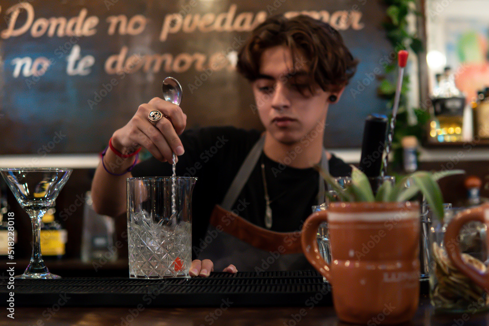 Waiter preparing a drink mixing with a shaker. Bartender at the bar counter preparing a drink