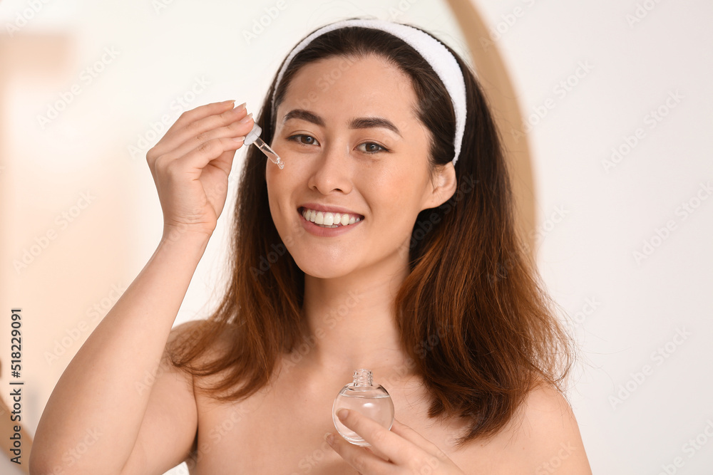 Young Asian woman using cosmetic serum in bathroom Young Asian woman using cosmetic serum in bathroom
