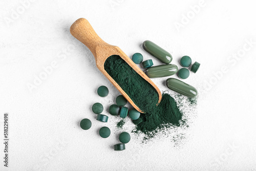 Scoop of spirulina powder and pills on white background photo