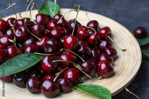 Plate with ripe cherries on table, closeup