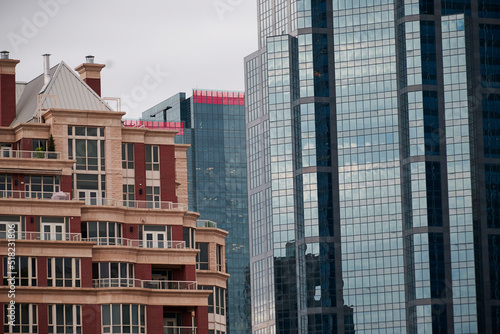 Skyscrapers in the city of Calgary large old red and yellow bricks with large balconies large different chimneys next to a modern building with large reflective windows top of the building with red il