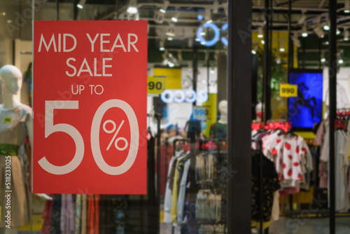 Discount percentage red sign display in fashion department store during sale season period. Sale tag of offering special promotion hanging in shopping mall, in department store background.
