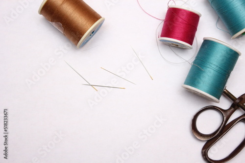 Multi-colored threads and old scissors spread out on a white floor, retro scissors, flat lay, copy space.