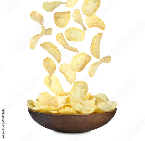 Fried crispy potato chips falling into bowl on white background