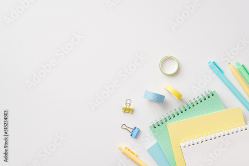 School supplies concept. Top view photo of stationery stack of notepads pens binder clips and adhesive tape on isolated white background with copyspace