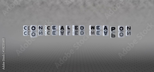 concealed weapon word or concept represented by black and white letter cubes on a grey horizon background stretching to infinity