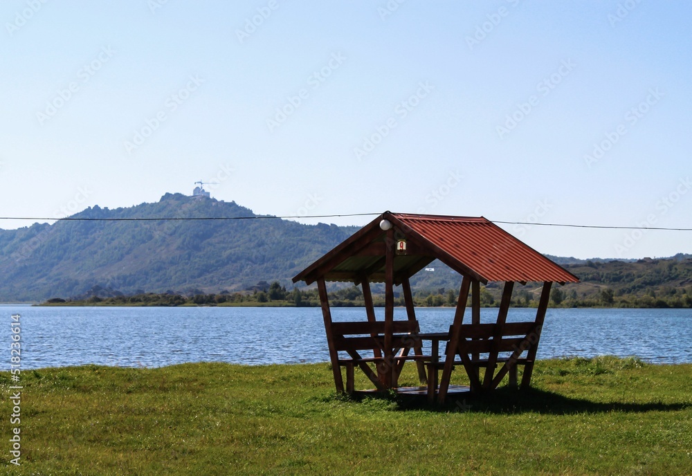 Empty gazebo on the shore of calm lake in summer time