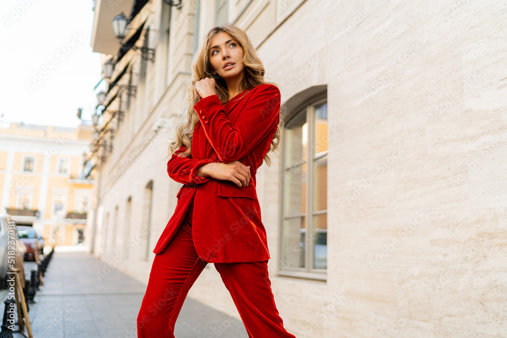 Obraz premium Profeshional fashion model in elegant red velvet suit posin outdoor in old european city.