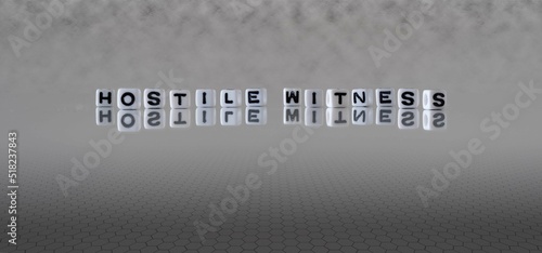 Φωτογραφία hostile witness word or concept represented by black and white letter cubes on a