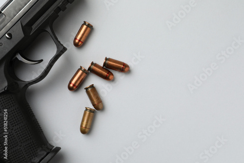 Semi-automatic pistol and bullets on light background, flat lay. Space for text photo