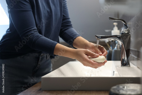Woman with soap bar washing hands in bathroom  closeup