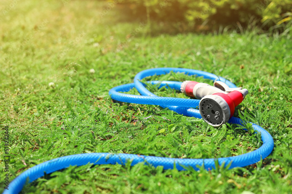 Watering hose with sprinkler on green grass outdoors, space for text