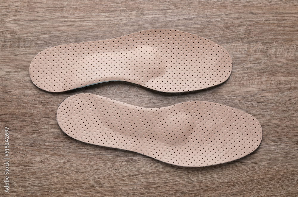 Beige orthopedic insoles on wooden background, flat lay Beige orthopedic insoles on wooden background, flat lay