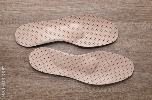 Beige orthopedic insoles on wooden background, flat lay