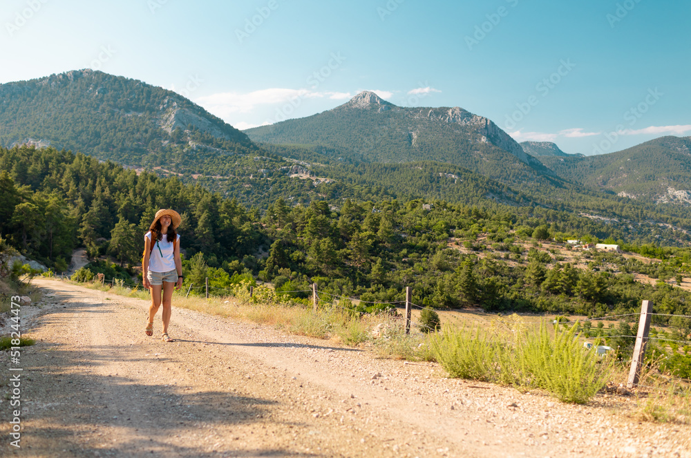 girl traveler with a backpack goes along a mountain path..