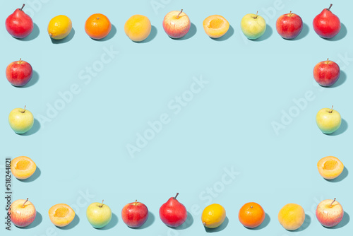 Creative summer frame made of ripe fruits on a mint background.