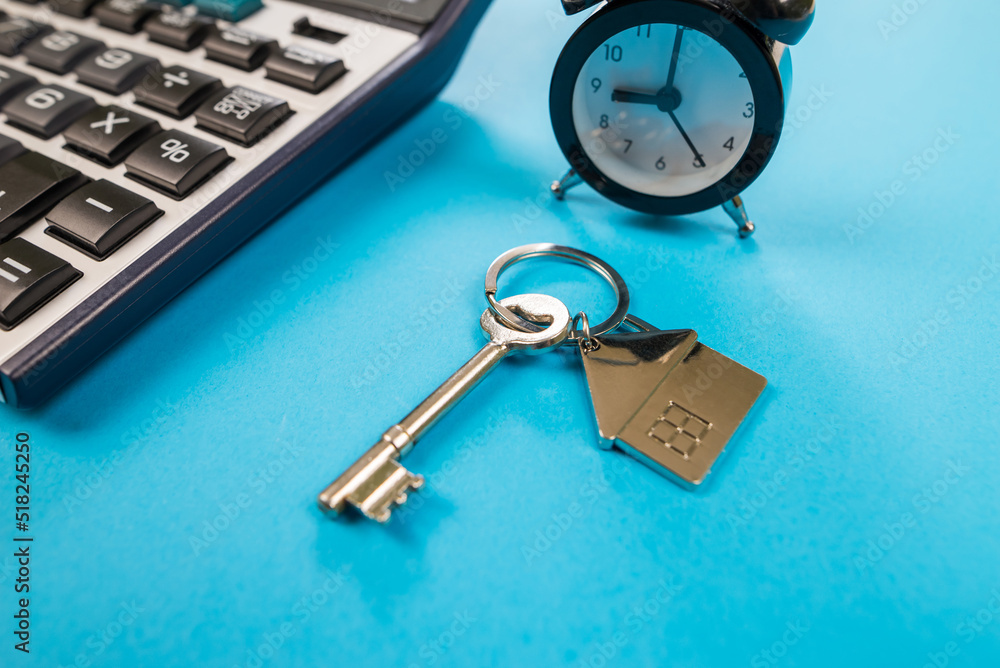 Apartment house key with calculator concept to calculate expenses, loan or insurance with copy space Apartment house key with calculator concept to calculate expenses, loan or insurance with copy space