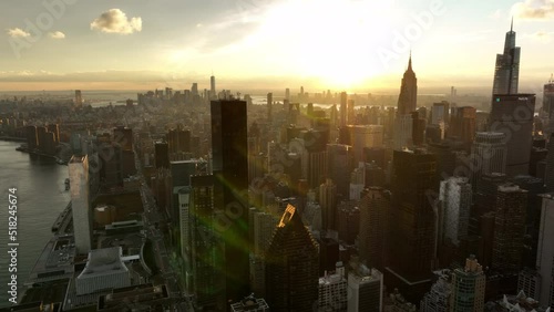 Fly above city at sunset. Aerial panoramic view of high rise buildings and skyline with skyscrapers against colourful sky. Manhattan, New York City, USA