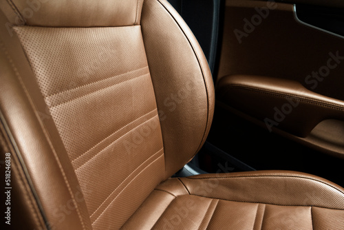 Modern luxury car brown leather interior. Part of brown perforated leather car seat details with white stitching. Interior of prestige car. Comfortable perforated leather seats. Perforated leather. © Aleksei