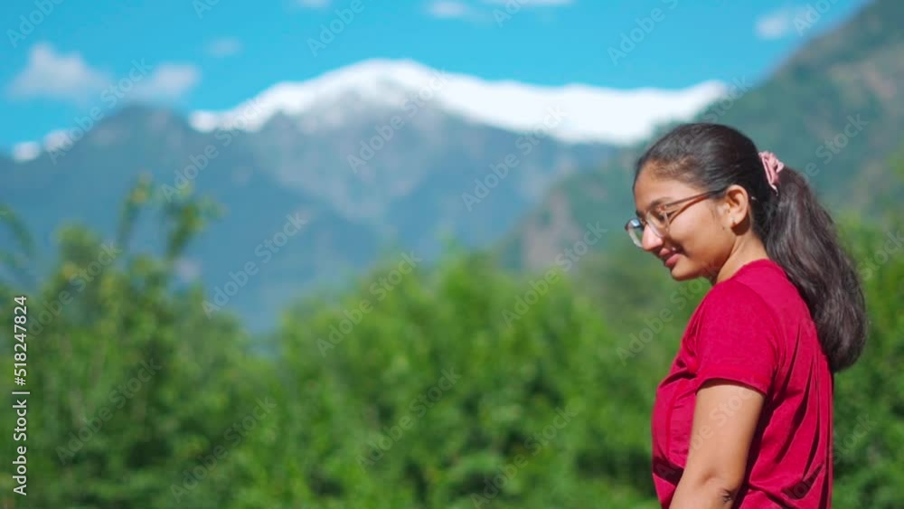 Portrait of beautiful Indian teenager girl enjoying summer day sunlight in background of snow capped mountains during summer in Manali, Himachal Pradesh, India. Female tourist relaxing during holiday Portrait of beautiful Indian teenager girl enjoying summer day sunlight in background of snow capped mountains during summer in Manali, Himachal Pradesh, India. Female tourist relaxing during holiday