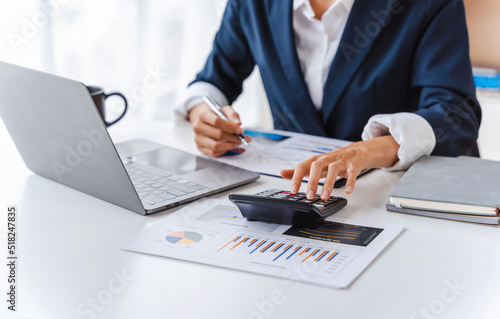 Close up accountant business woman using laptop at workplace with financial reports.