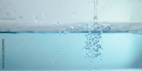 de-focused. Closeup of light blue transparent clear calm water surface texture with splashes and bubbles. Trendy abstract summer nature background. for a product, advertising,text space.