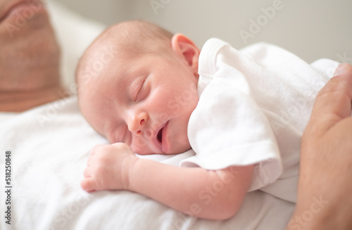 Baby sleeping soundly and peacefully on father's chest. Birth kid - happiness for family. New worries and style life. Concept of child care, feeling safe, parent love.