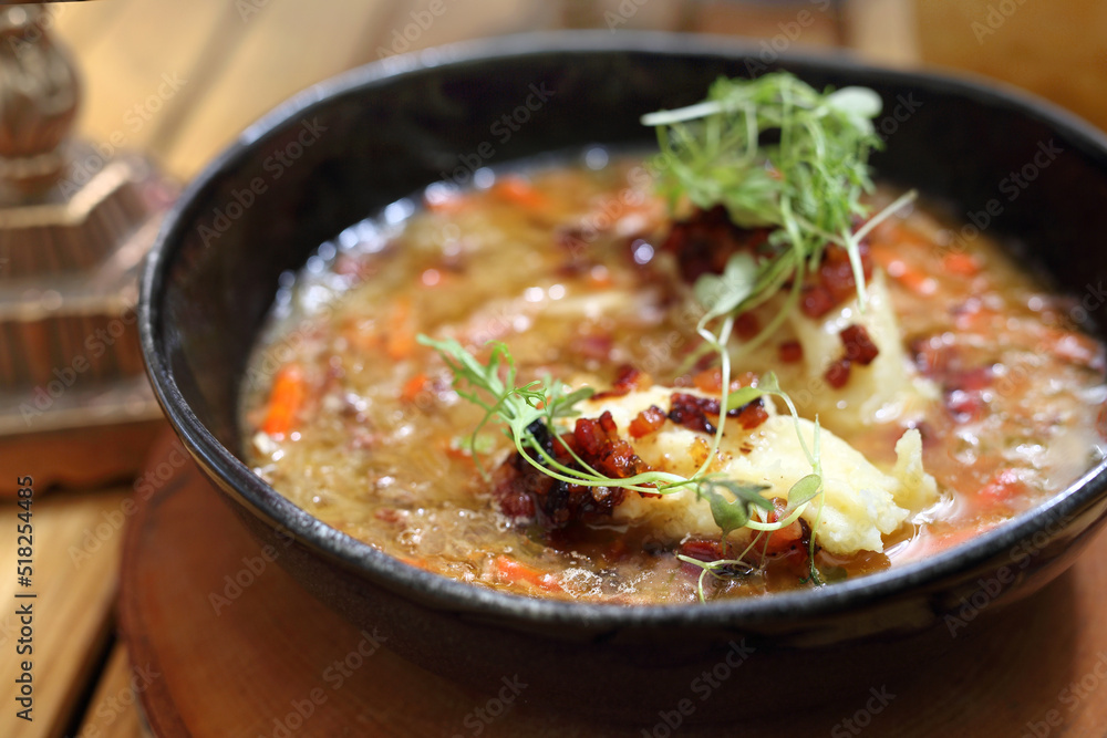 Close-up of dumplings in a sauerkraut soup, selective focus. Cabbage soup in a modern black bowl, on a wooden table.