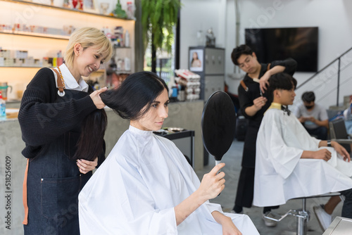 Asian hairdresser team give service beauty and treatment to customers. Professional stylist male and woman hair design and using scissors cutting hair to consumer with smile in beauty salon or barber.
