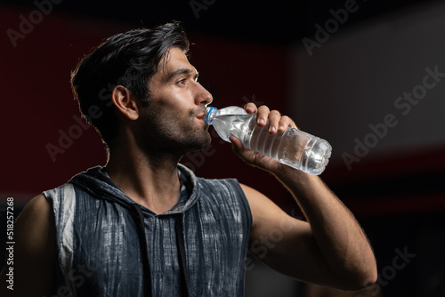 Caucasian active young man take a break drink water after exercise. Attractive handsome male in sportswear standing and sip water while breaking after body weight from exercise machines in gym fitness