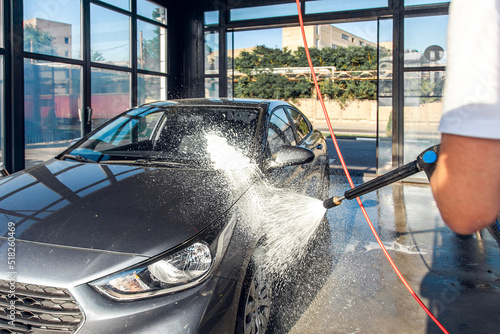 Obraz na płótnie Self-service car wash. A man waters his car with foam from a pressurized hose w salonie