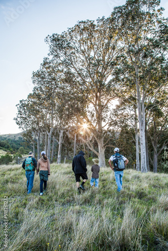 Group of bushwalkers hiking through a paddock at sunrise