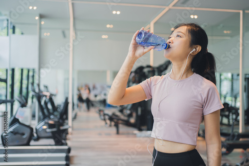 Asian beautiful woman drink water in the gym after exercise.