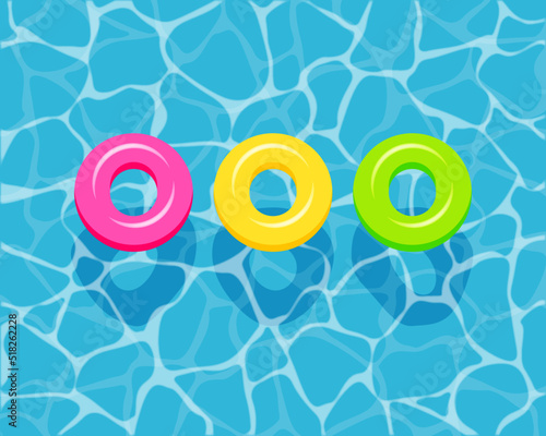 Top view of colorful swim rings on the blue water background