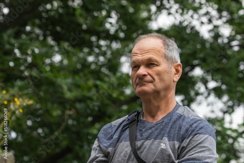 Portrait of wise smiling caucasian senior man in casual clothing. Isolated on the nature background.