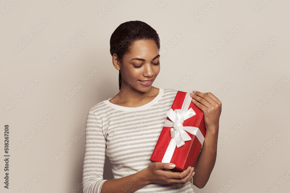 Happy young African American woman with red gift present box in her hands on white background